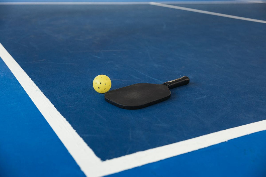 A pickleball paddle and ball resting on a blue court